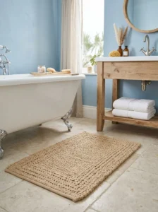 andy beige textured bath mat adding warmth to a soft blue-and-white coastal bathroom.