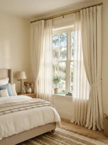Bedroom windows styled with layered sheer and heavier ivory linen curtains.