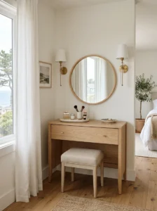 Nancy Meyers-inspired bedroom vanity with round mirror and light wood dresser.