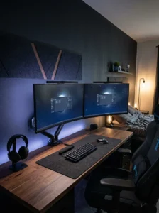 Dual monitor gaming bedroom setup with monitor arms, bias lighting and organized desk.