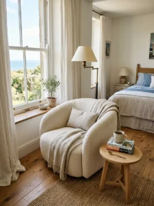Cozy bedroom reading nook with boucle chair, books, floor lamp, and window light.