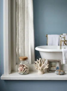 Small glass jar of seashells displayed tastefully on a coastal bathroom windowsill.
