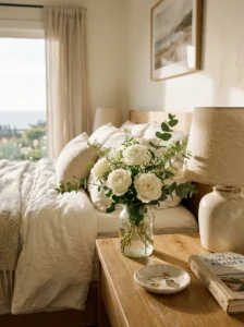 Fresh white flowers and eucalyptus styled on an elegant bedroom nightstand.