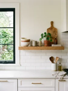 Thoughtfully styled open kitchen shelf with ceramics, wood accents, and greenery.