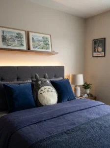Character cushion styled thoughtfully with neutral pillows on an anime bedroom bed.