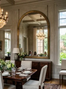 Oversized arched brass mirror in an elegant dining room.